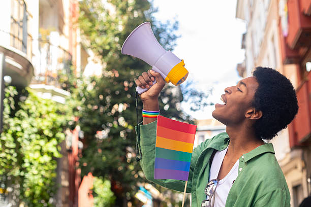 Young activist shouting with megaphone at pride parade promoting lgbtq plus rights