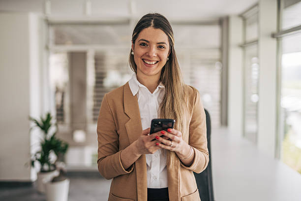 istock Smiling businesswoman using smartphone in modern office 2207743532