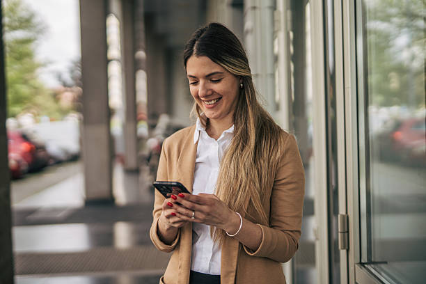 istock Smiling businesswoman using smartphone in a modern urban setting 2207743752