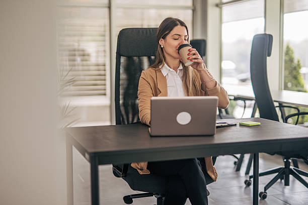 istock Businesswoman drinking coffee while working on laptop in office 2207743818