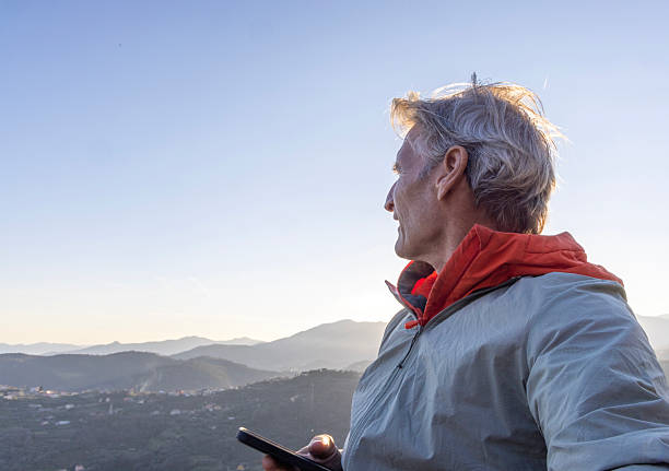 istock Mature man uses mobile phone on mountain top 2207743851