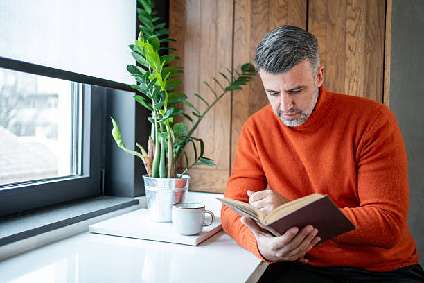 istock Mid adult man reading a book and relaxing at home 2207744005