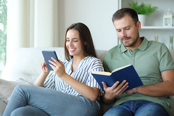 Couple reading paper book and ebbok at home