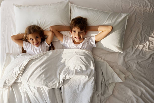 istock Above view of happy siblings relaxing in a bed. 2207747381