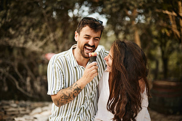 Cheerful couple having fun while eating ice cream in summer day.