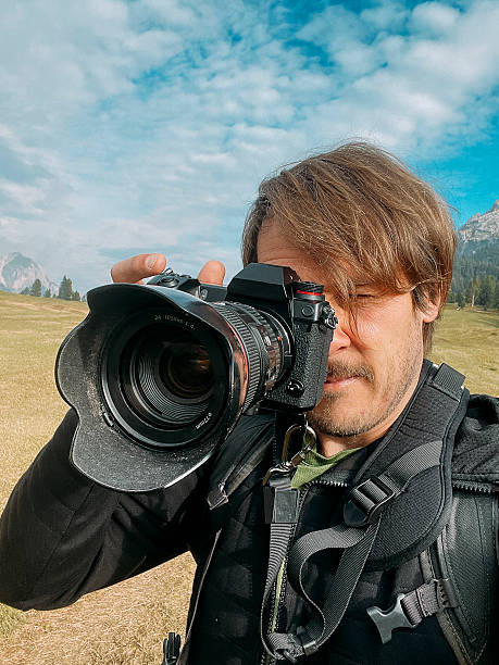 istock Man holding camera while capturing outdoor landscape in mountainous setting 2207749689