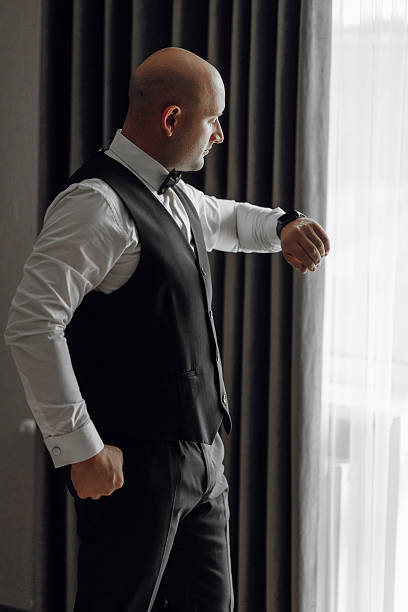 istock A man in a suit and vest is looking at his watch 2207752047