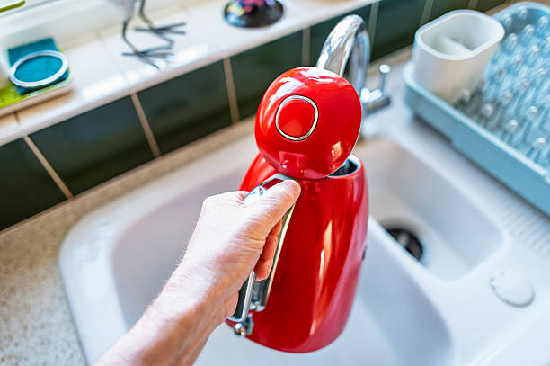 istock Homeowner seen filling a stylish water kettle at a kitchen sink. 2207752191