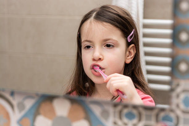 istock Girl brushes her teeth while looking in the mirror 2207753810