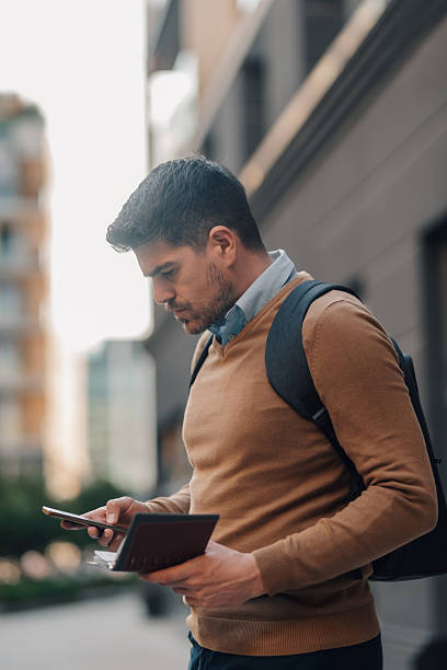 istock Businessman using smartphone and holding wallet in urban setting 2207754410