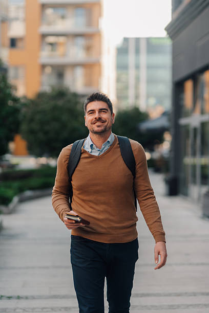 istock Smiling businessman walking in the city with backpack and notebook 2207754701