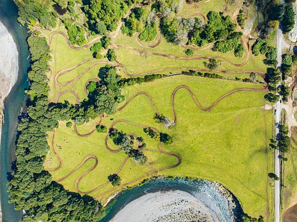 istock Aerial view of winding dirt track through lush fields. 2207757221