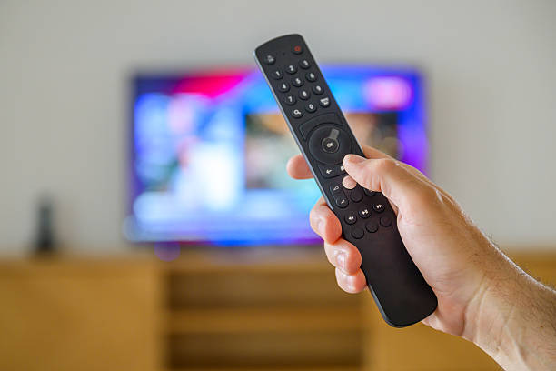 istock Male hand with a TV remote controller in living room 2207757779