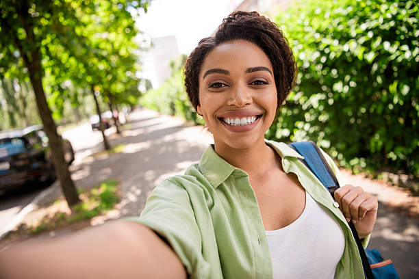 istock Smiling woman taking a selfie while walking in a sunny green park 2207758040