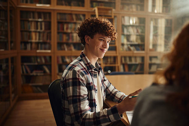 istock Smiling male student talking to his friend in library. 2207760833
