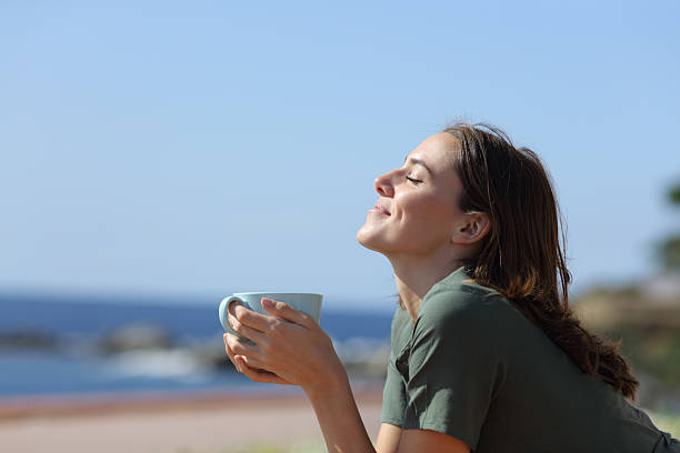 istock Woman drinking coffee or tea breathing on the beach 2207761760