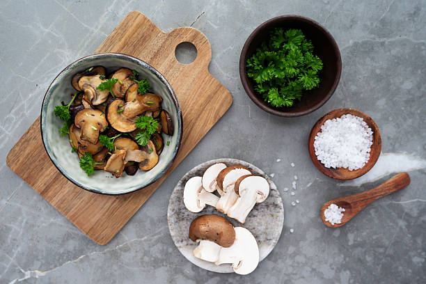 istock Golden mushroom slices stacked on a plate, with fresh whole champignons. 2207762199