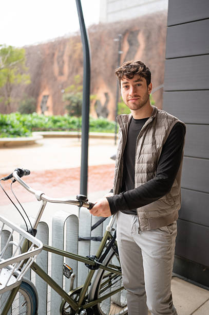 istock Young man holding handlebars of his bicycle in urban setting 2207762603