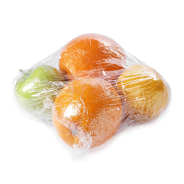 Fresh fruits with plastic food wrap isolated on white