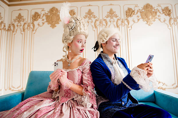 istock Elegant couple in baroque costumes using modern technology in a luxurious historical interior 2207764144