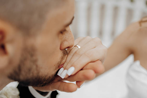 A man kisses a woman's hand, both wearing wedding rings. Concept of love and affection between the couple, as they share a tender moment together
