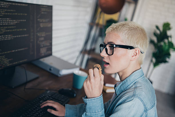istock Young woman programmer working with code and enjoying a snack in a stylish home office environment 2207764684