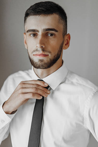 istock A man in a white shirt and black tie is posing for a photo 2207765018