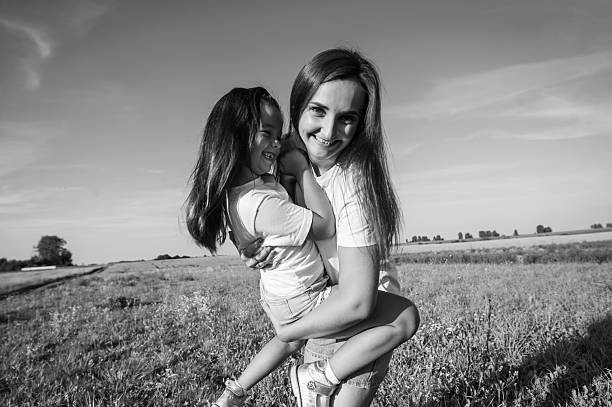 Beautiful weather highlights the joy that surrounds them. Cheerful girls feel harmony and comfort. The meadow stretches like a blooming carpet under the summer sky.