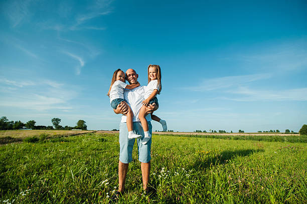 istock The father lovingly lifts two sisters into the air 2207766072