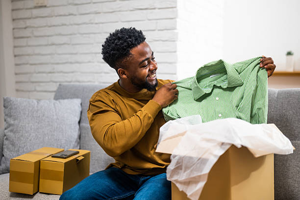 istock Delighted African customer unwrapping new clothing order at home 2207767329