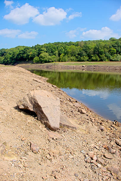 After a hot summer not much water remaining in a reservoir in the Lancashire countryside, North West England, UK. The view is looking across part of the reservoir bed which would normally be under deep water.