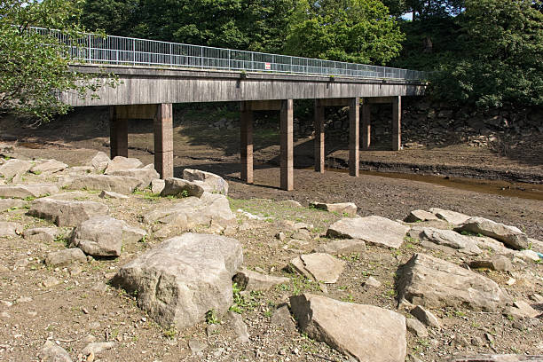After a hot summer not much water remaining in a reservoir in the Lancashire countryside, North West England, UK. The view is looking across part of the reservoir bed which would normally be under deep water.