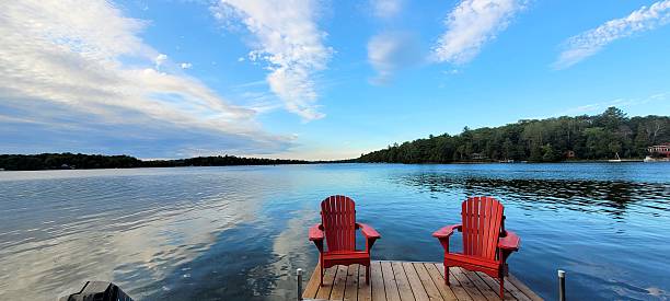 istock Lake Escape: Red Lounge Chairs on a Serene Boat Dock 2207768860