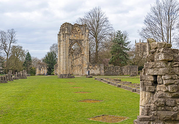 Majestic medieval cathedral with Gothic architecture, towering amidst leafless trees under a blue sky with fluffy clouds, ideal for historical or travel themes in York, North Yorkshire, England.