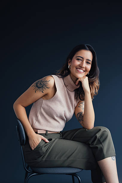 istock Confident Woman Smiling in Relaxed Pose With Tattoo in Minimalist Setting 2207770991