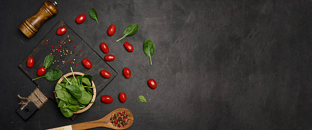 istock Fresh spinach leaves, cherry tomatoes, and mixed peppercorns on a black background. Copy space 2207771227