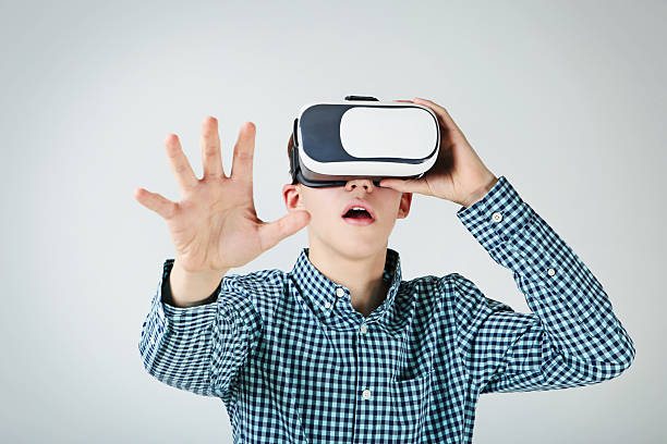 istock Young boy in virtual reality goggles on grey background 2207773384