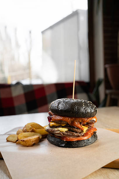 istock large appetizing burger with black bun on table in cafe 2207787176