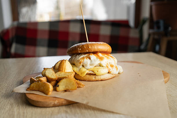 Delicious grilled hamburger with potato wedges on wooden board.