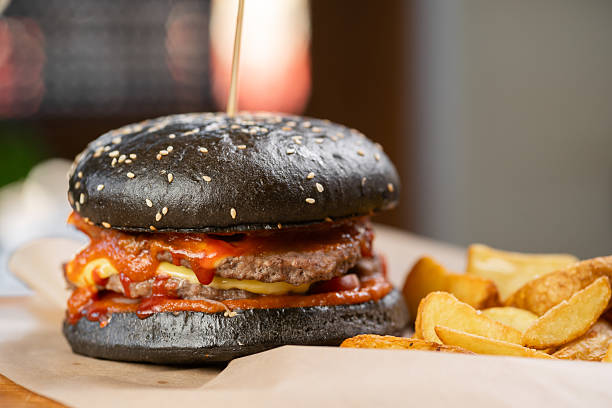 istock hamburger with black beef bun with sauce and fries located on table indoors 2207787205