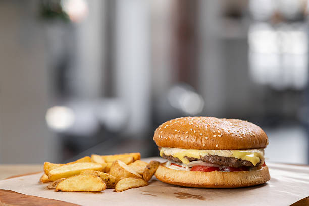 burger and fries served in plate on wooden board.