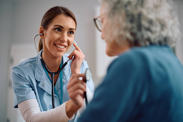 istock Happy doctor using with stethoscope while examining her senior patient on a house call. 2207787271
