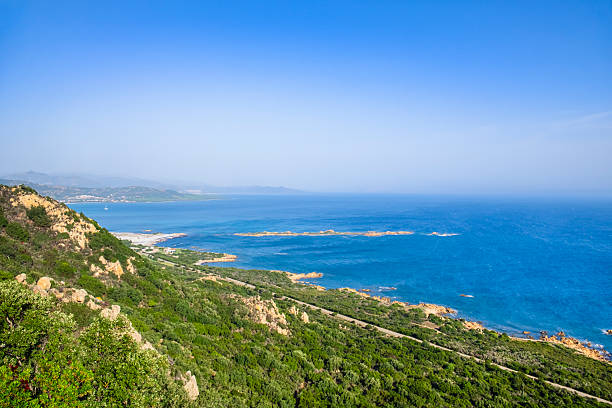 Rocky coastline of Capo Comino with the island of Ruja, a red porphyry skerry reachable swimming or walking