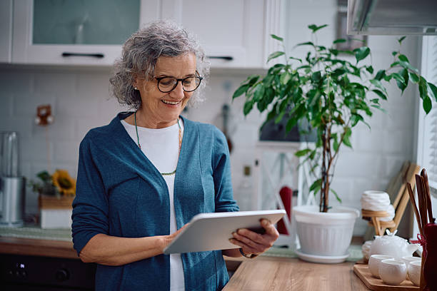 istock Happy senior woman using digital tablet in kitchen. 2207787390