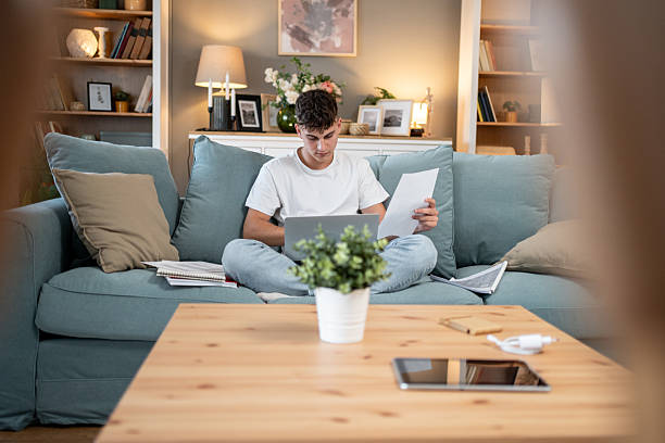 istock Young man working from home on laptop and reading documents 2207788746