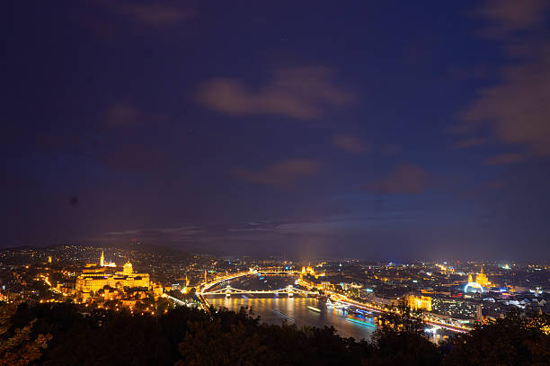 Panoramic view of Budapest glowing at night, with Buda Castle, Chain Bridge and Hungarian Parliament Building illuminated, seen from Citadella viewpoint, Hungary