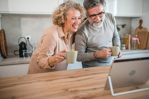 istock Carefree married couple using laptop while standing at kitchen counter drinking coffee 2207794132