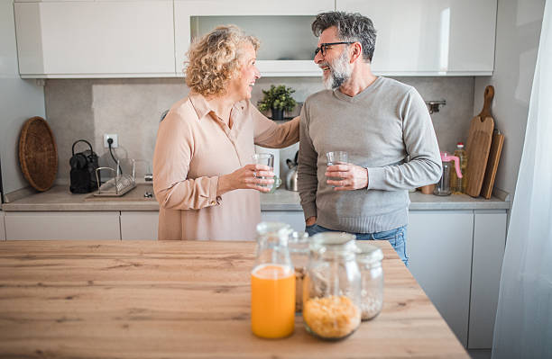 istock Carefree mature couple refreshing themselves by drinking water while standing at the kitchen counter 2207794150