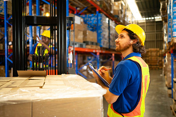 istock A warehouse worker inspects inventory with a clipboard, ensuring efficient operations and safety in a busy environment. 2207794157