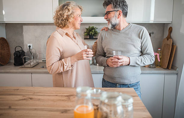 istock Cheerful mature couple refreshing themselves by drinking water while standing at the kitchen counter 2207794463